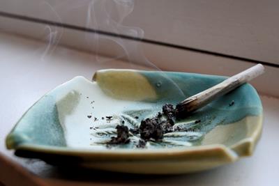Image of a cannabis joint smoking in a turquoise and yellow ash tray