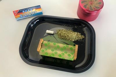joint roller on a rolling tray with weed, rolling papers, and a grinder