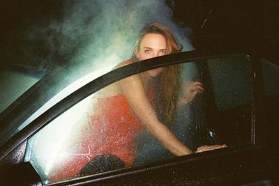 A women walking out of a hotboxed car with a cloud of smoke surrounding her