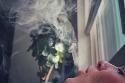Person exhaling cannabis smoke from a joint