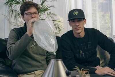 Picture of two people enjoying a smoke session from a table top Volcano, Balloon Vaporizer, with the bag full of vapor being inhaled