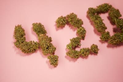 420 spelled out in army green colored nuggets with a baby pink background