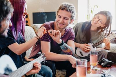 Image of a group of friends sharing a joint and playing guitar.