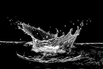 Water dropping into a pool of water with a ripple effect and splash, in front of a black background!